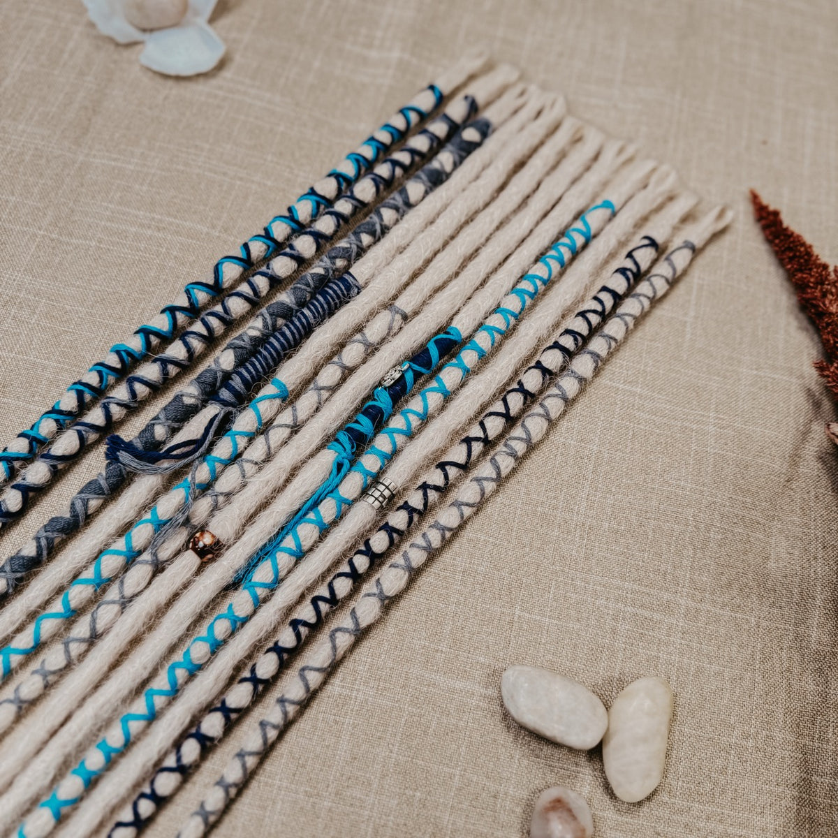 Decorated Dreadlock Extensions: ash blonde, white silver dreads with blue and gray decorations. Accent Set from Dreadshop. Close up on top