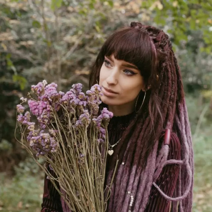 Emitsem holding purple flowers and wearing the dreadset Lavender burst in Bum length, Dreadset Locks of Love Shop the look, dreadset full head, Dreadset original locks of love
