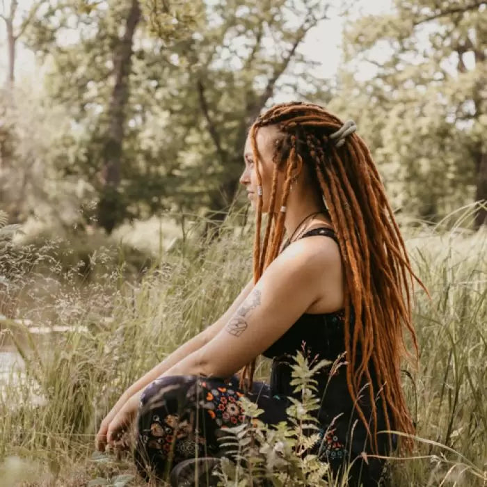 Romy from the side sitting in the grass wearing the dreadset Go ginger in Bum length, Dreadset Locks of Love Shop the look, dreadset full head, Dreadset original locks of love
