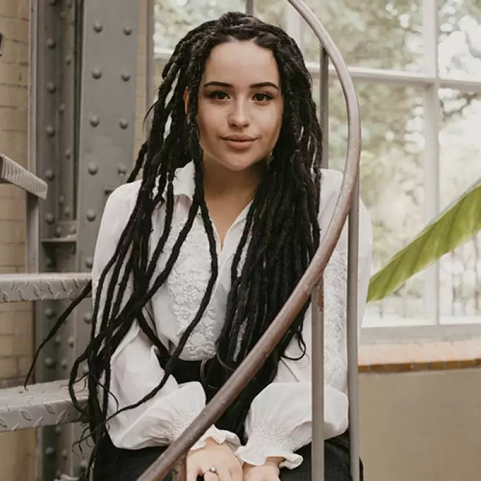 Romy sitting on the stairs wearing the dreadset Midnight in Bum length, Dreadset Locks of Love Shop the look, dreadset full head, Dreadset original locks of love