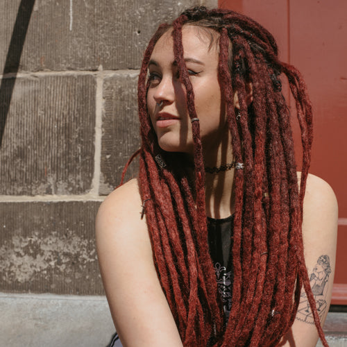 Romy looking away while wearing the dreadset Maroon in Bum length, Dreadset Locks of Love Shop the look, dreadset full head, Dreadset original locks of love