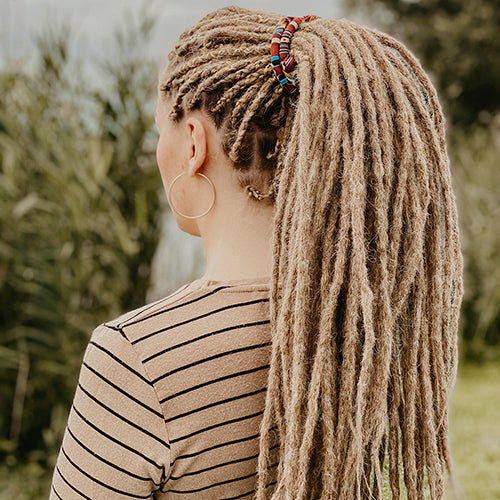 Renate from the back, wearing her dreads in a spiralock. she is wearing the dreadset Thin Dark blonde in Bum length, Dreadset Locks of Love Shop the look, dreadset full head, Dreadset thin locks of love