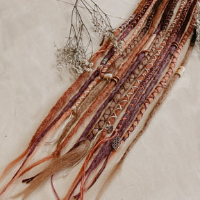 A set of handmade bohemian decorated dreadlock extensions Locks of Love in different colors, pink lavender purple and dark brown caramel tones. Close up on the decorations