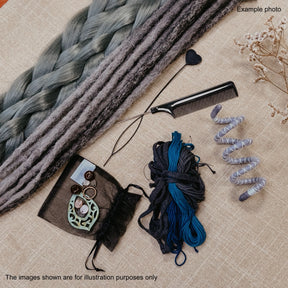 A styled flat-lay of hair extension or wig materials on a beige fabric background, including a large braided section of gray-green synthetic hair, a black comb, a small black heart clip, a bundle of dark blue and black yarn, a coiled gray-green hair sample, and a black drawstring pouch with a decorative keychain. Text notes that the images are for illustration purposes only.