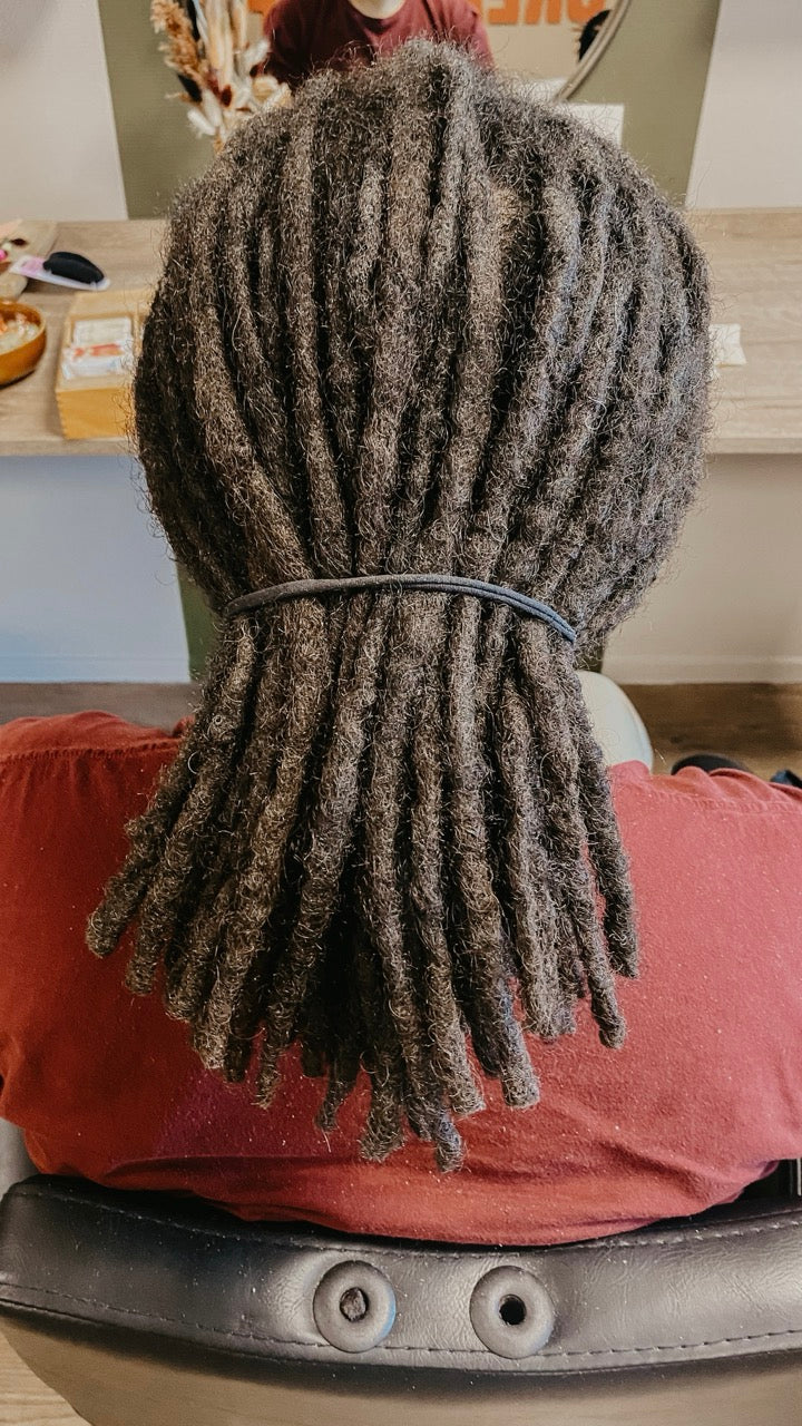 Person with real dreadlocks sitting in a salon chair in Dreadshop Salon. Short dark dreadlocks 